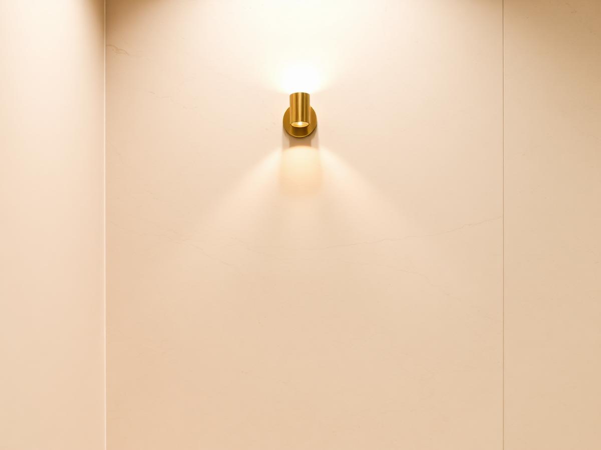 Interior da Aurea Clínica em Brasília — mármore travertino e iluminação dourada